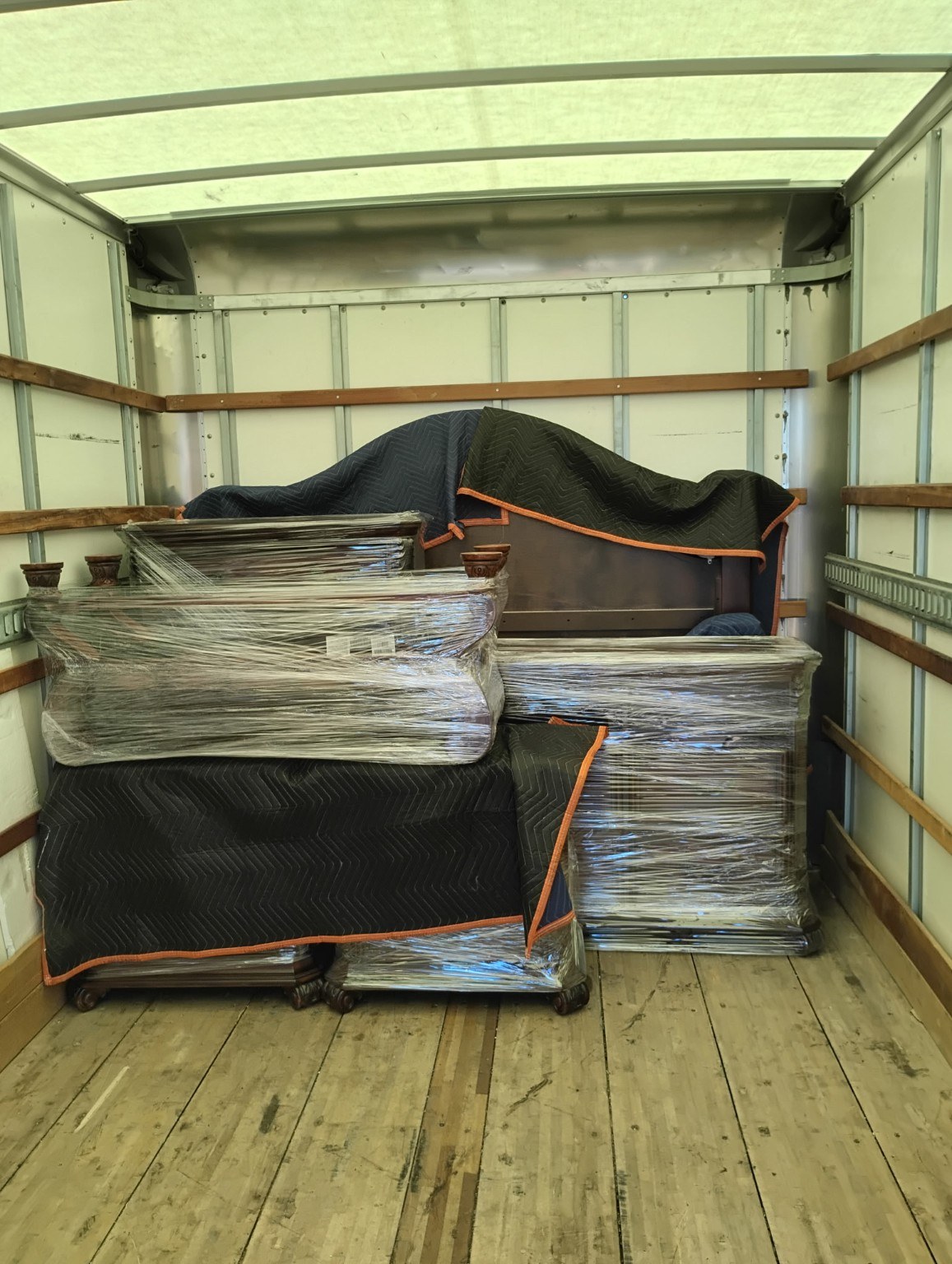 Furniture wrapped in plastic and moving blankets inside a box truck